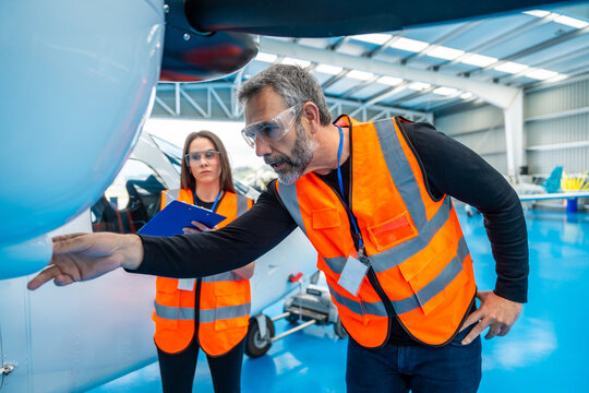 Aviation engineers inspecting aircraft in hangar for maintenance