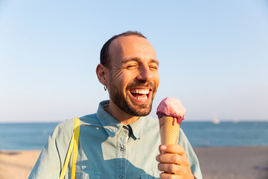 Tourist laughing with melting ice cream cone at Barcelona beach