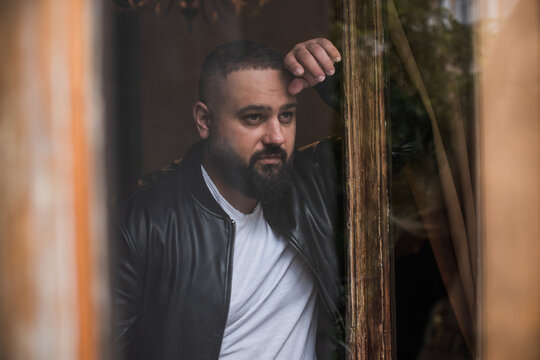 Sad and thoughtful mid adult man facing depression, lonely Caucasian or Arabic male looking away with anxiety, mental health and psychological burnout concept in a moody urban setting