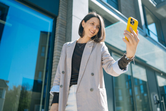 Smiling professional taking selfie outside modern office building