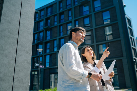 Realtor pointing at apartment building while discussing property