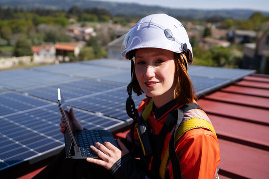 Smiling technician inspecting solar panel on rooftop with tablet