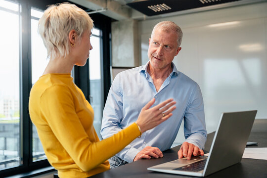 Colleagues discussing business strategy at the office with laptop