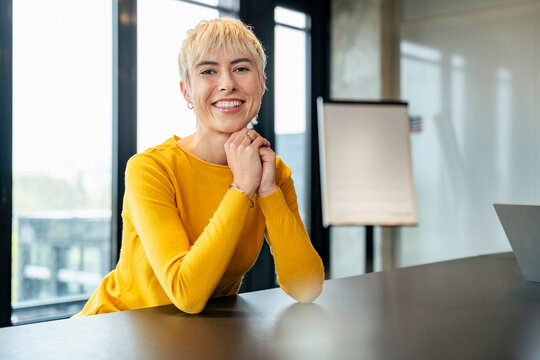 Smiling manager sitting at desk in modern office