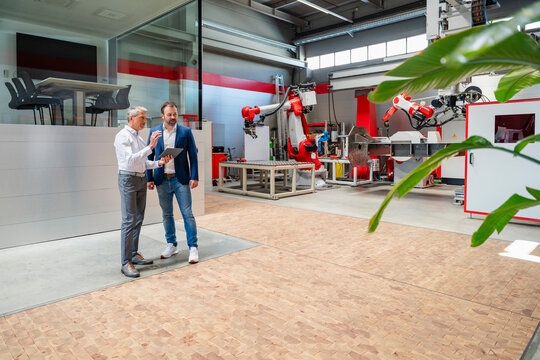 Engineers discussing planning on tablet in modern automation factory