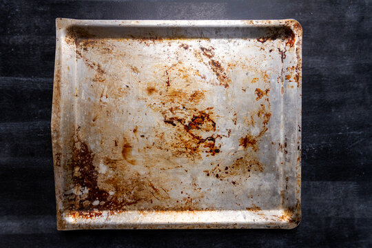 Used oven flat baking pan with burned spots and scratches on black chalkboard background