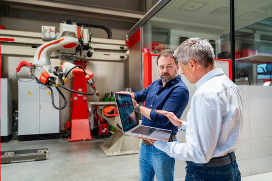 Employee and manager discussing planning on laptop in factory