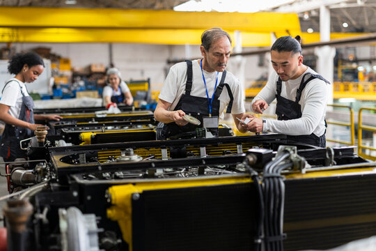 Mechanics inspecting an engine indoors at a manufacturing plant