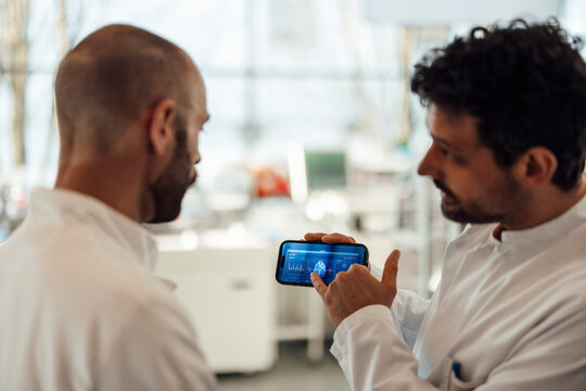 Scientists discussing brain research data on smartphone in laboratory