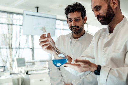 Scientists examining blue liquid sample in laboratory