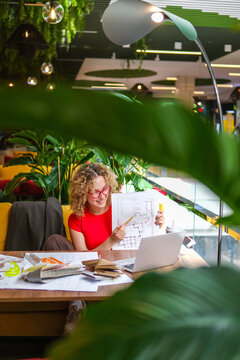 Architect presenting blueprint on video call in biophilic office