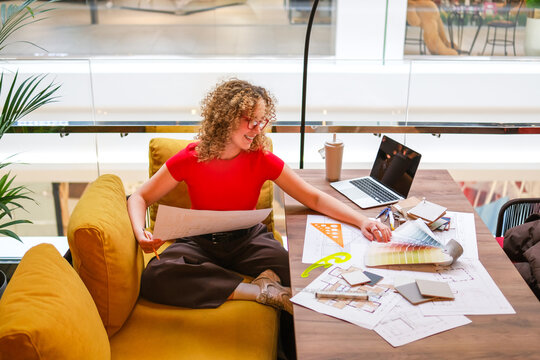 Architect reviewing blueprint and laptop in modern workspace