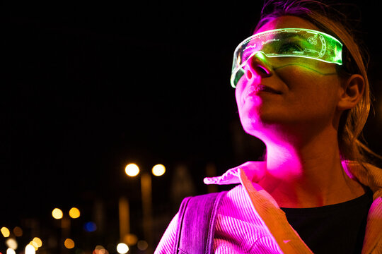 Woman looking through augmented reality visor in neon city at night