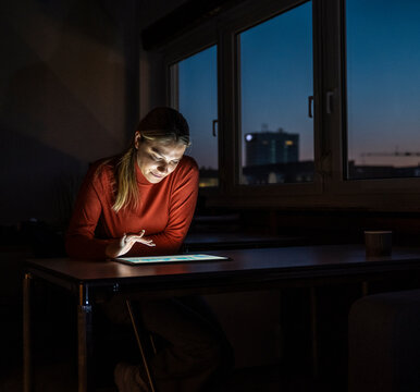 Employee working on tablet in dark office at night