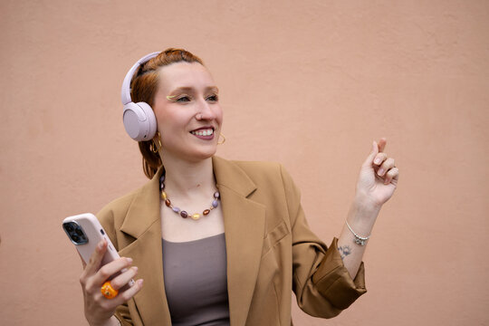 Smiling woman listening to music on smartphone outdoors