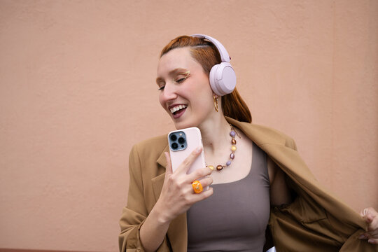 Smiling woman listening to music on smartphone outdoors