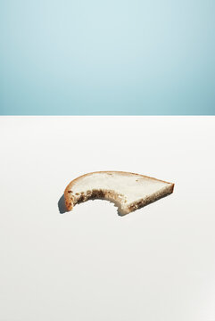 Bitten slice of bread with butter on a white and blue background