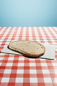 Slice of bread on chopping board over retro checkered tablecloth