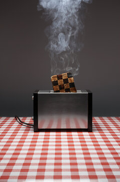 Smoking burnt toast with checkered pattern in toaster