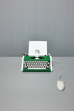 Retro typewriter connected to a computer mouse with save icon