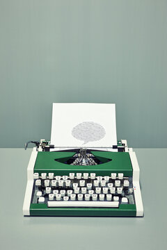Retro green typewriter with printed speech bubble and copy space