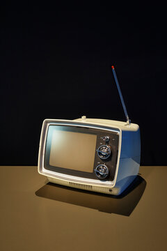 Retro portable television with antenna on dark background