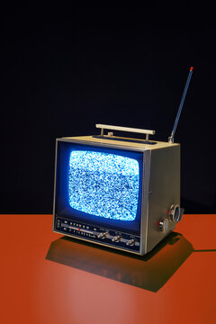 Vintage portable television with static on red surface