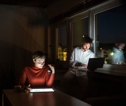 Two businesspeople working overtime at night in a dark office