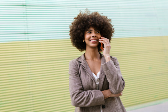 Cheerful female entrepreneur talking on smartphone outdoors