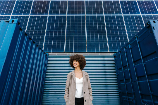 Smiling woman by solar panel and shipping container
