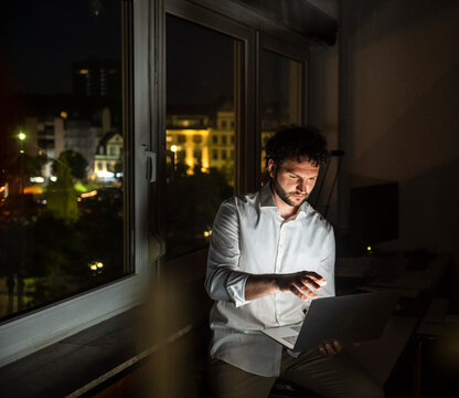 Businessman working on laptop by the window at night