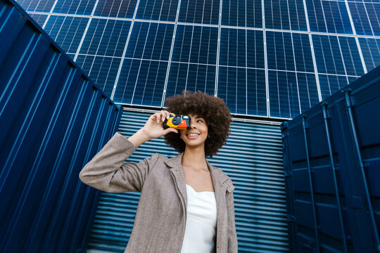 Cheerful photographer taking photo outdoors near solar panel
