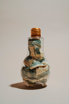 Lightbulb filled with crumpled dollar bills for innovation concept