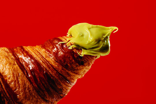 Flaky croissant with pistachio cream on red background