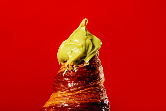 Croissant with pistachio cream on red background