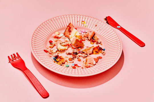 Messy birthday cake leftovers with confetti on a pink plate