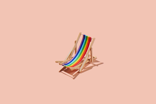 Rainbow striped beach chair on pastel pink background