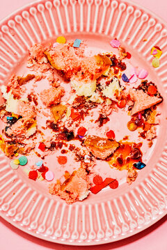 Messy cake leftover with confetti on pink plate after celebration