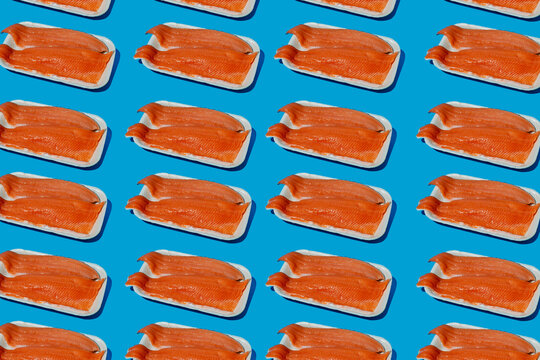 Packaged raw trout fillets repeating on a blue background