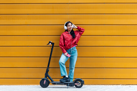 Woman with electric scooter and smartphone relaxing on street