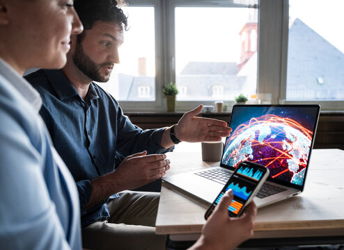 Business team analyzing global network data on laptop in office