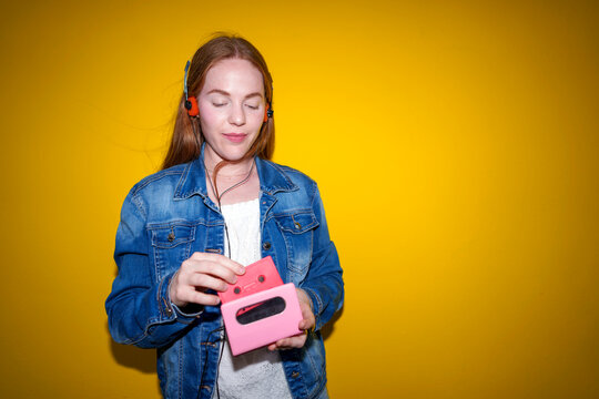 Redhead in denim jacket inserting cassette into personal stereo