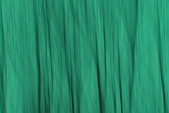 Soft motion blur background with vertical lines in warm green tints of trees through intentional camera movement 
