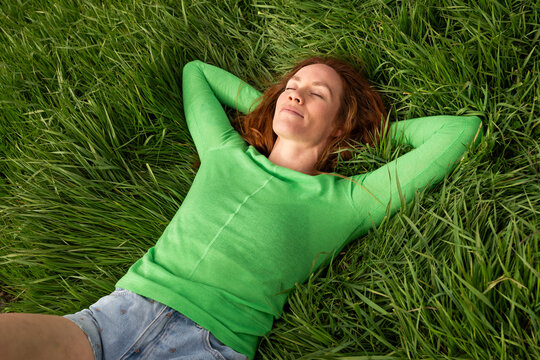 Relaxing on green grass with closed eyes in a field in Spain