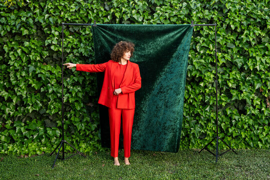 Model in orange suit posing in garden with green backdrop