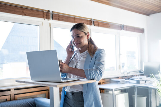 Manager talking on smartphone at standing desk in office