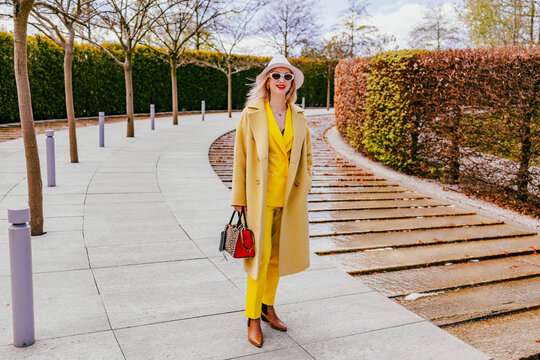 Happy freelancer walking in modern park wearing yellow suit and hat