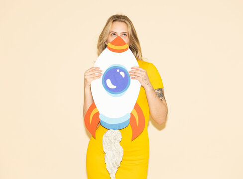 Model holding handmade paper rocket showing ambition and success