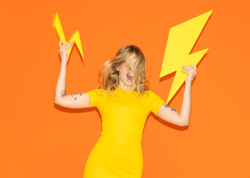 Model in yellow dress holding paper lightning bolt with high energy
