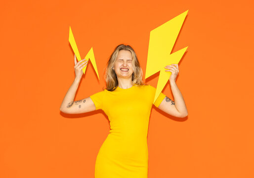 Model in yellow dress holding paper lightning bolt showing energy